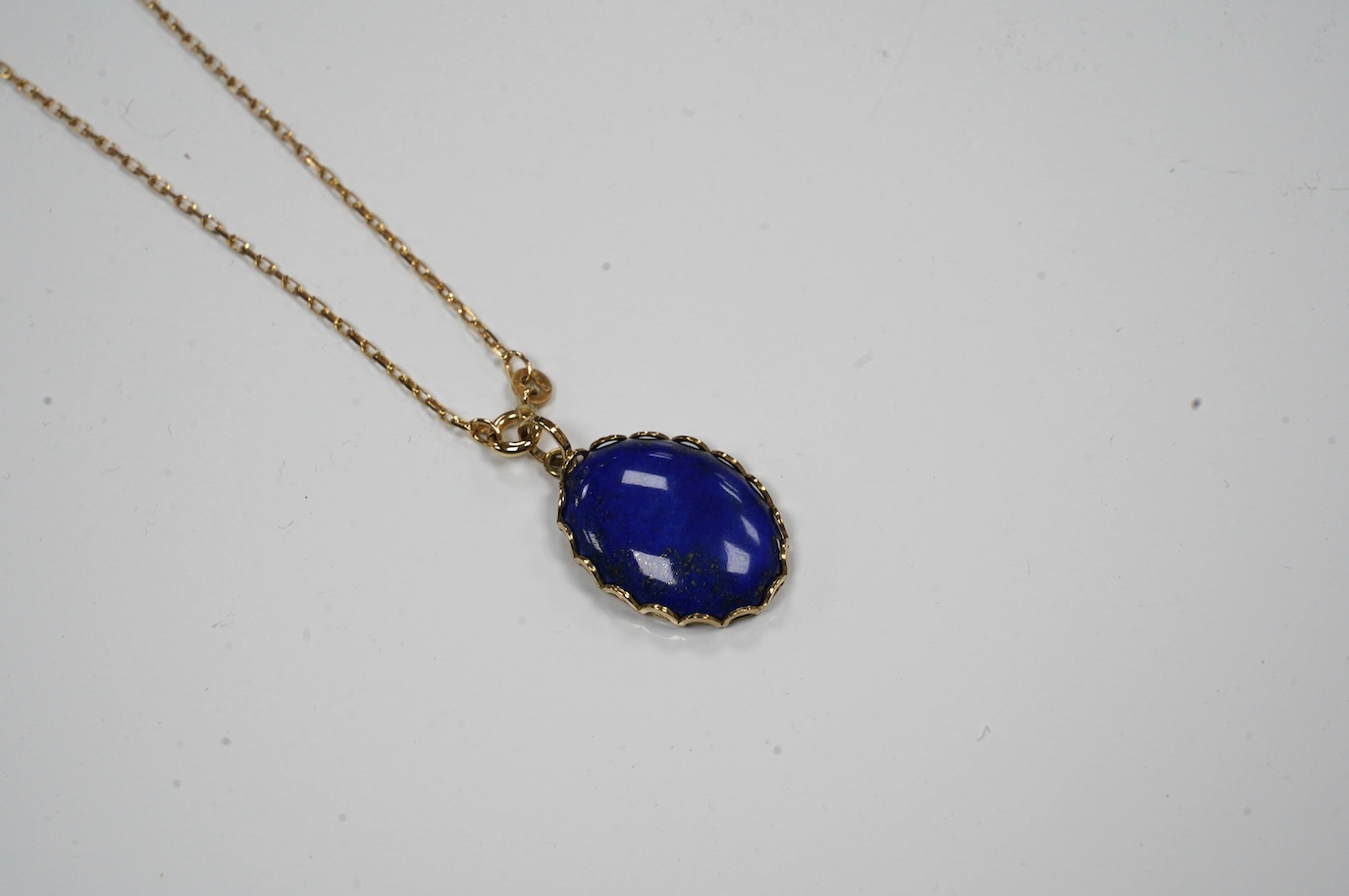 A modern 9ct gold mounted oval lapis lazuli pendant, 25mm, on a 9k fine link chain, 36cm, gross weight 8.2 grams. Condition - fair to good